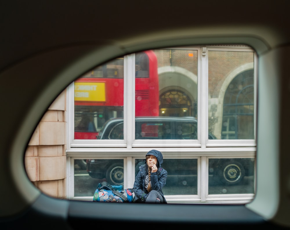 Une femme assise sur le rebord d’une fenêtre parle au téléphone portable