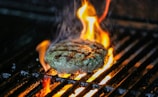a hamburger is cooking on a grill with flames
