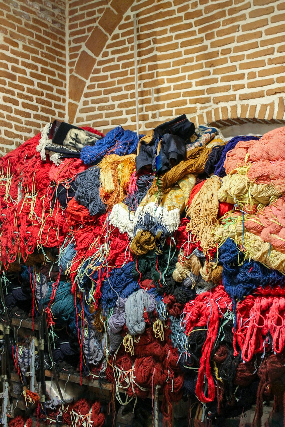 a pile of yarn sitting next to a brick wall