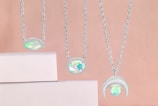 A layered necklace set featuring shimmering pendants resting on a soft fabric background.