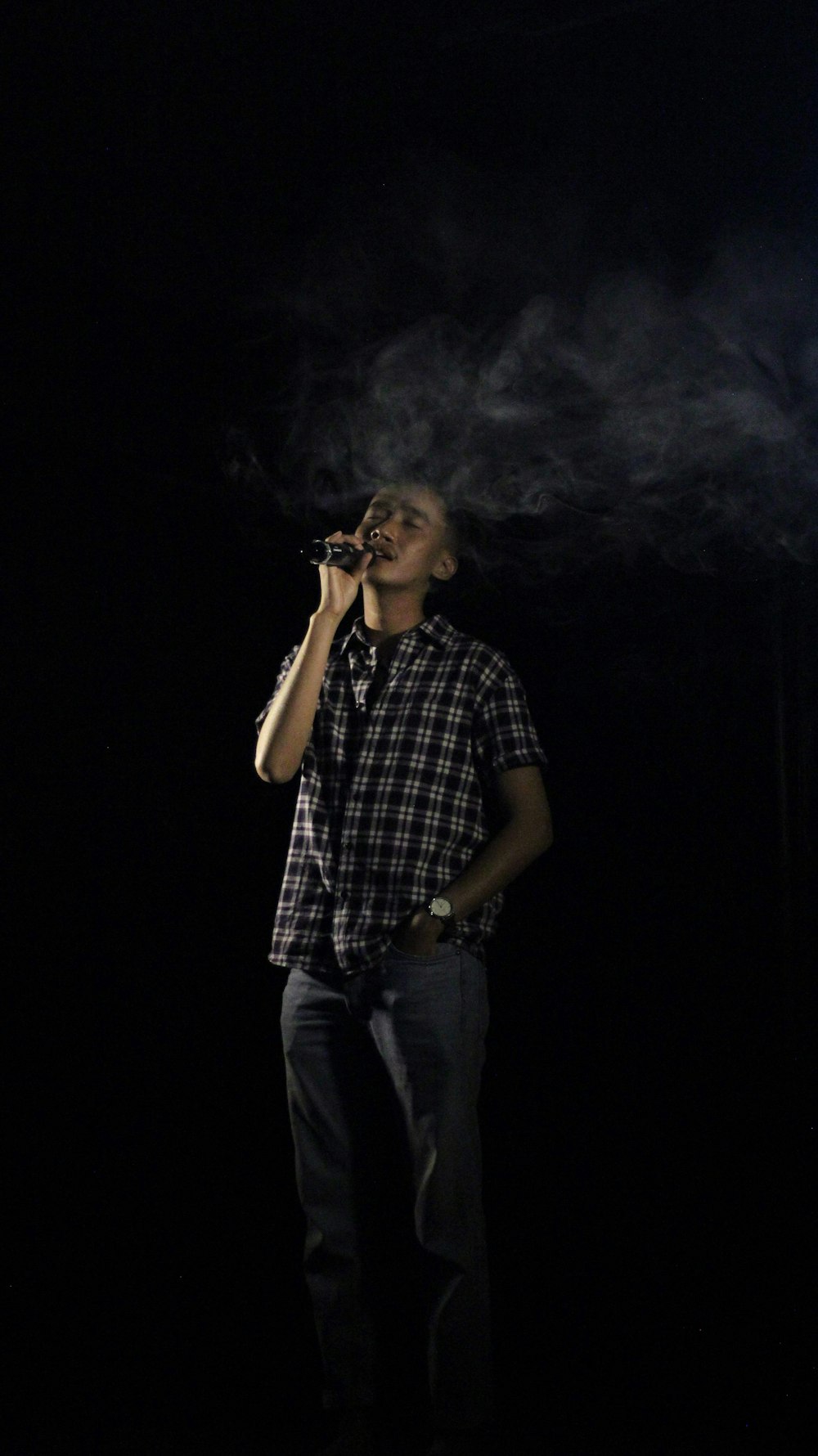 a man smoking a cigarette in the dark