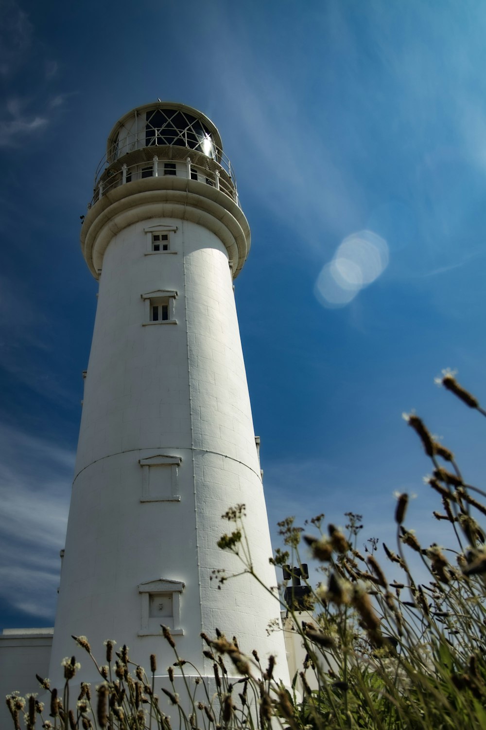 a tall white lighthouse sitting on top of a lush green field