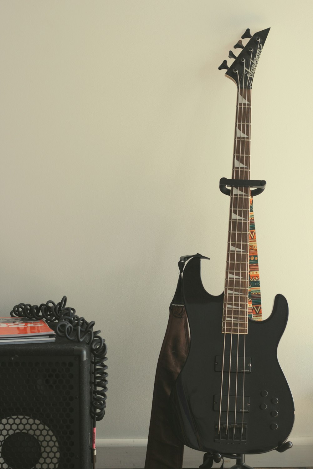 a black guitar sitting on top of a table next to a speaker