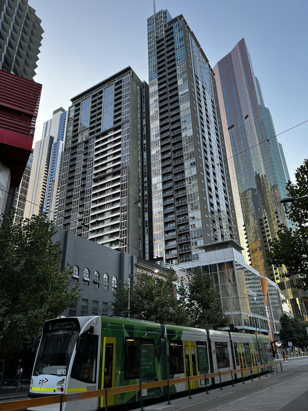 a green and yellow train traveling past tall buildings