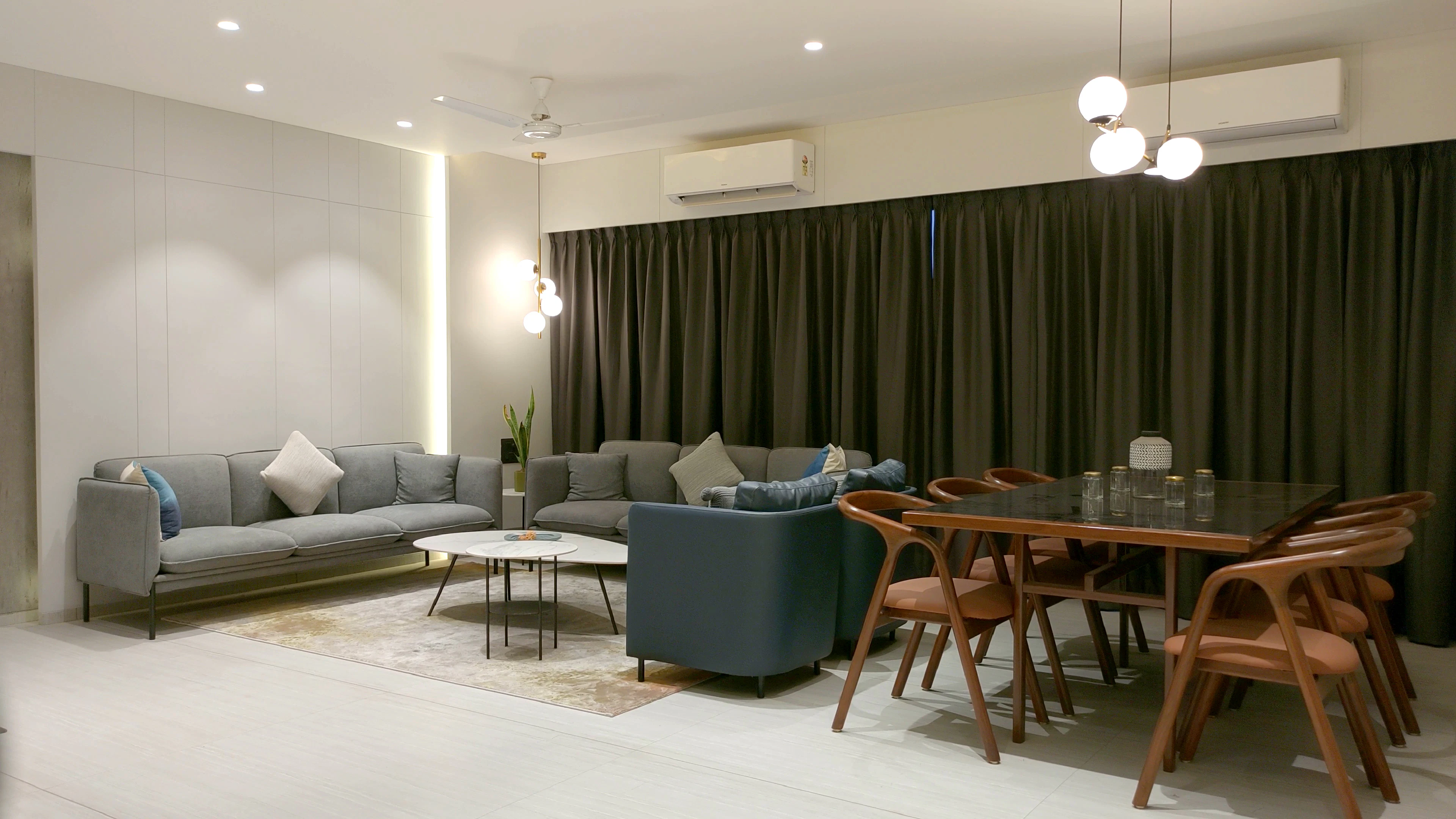 Living and dining area with grey sofas and a wall-mounted air conditioner