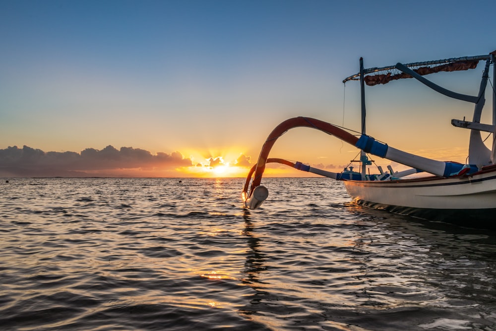 a boat in the water with the sun setting in the background