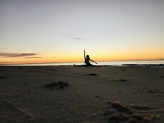 Sunset over a San Diego beach with a silhouette of a person doing assisted stretching