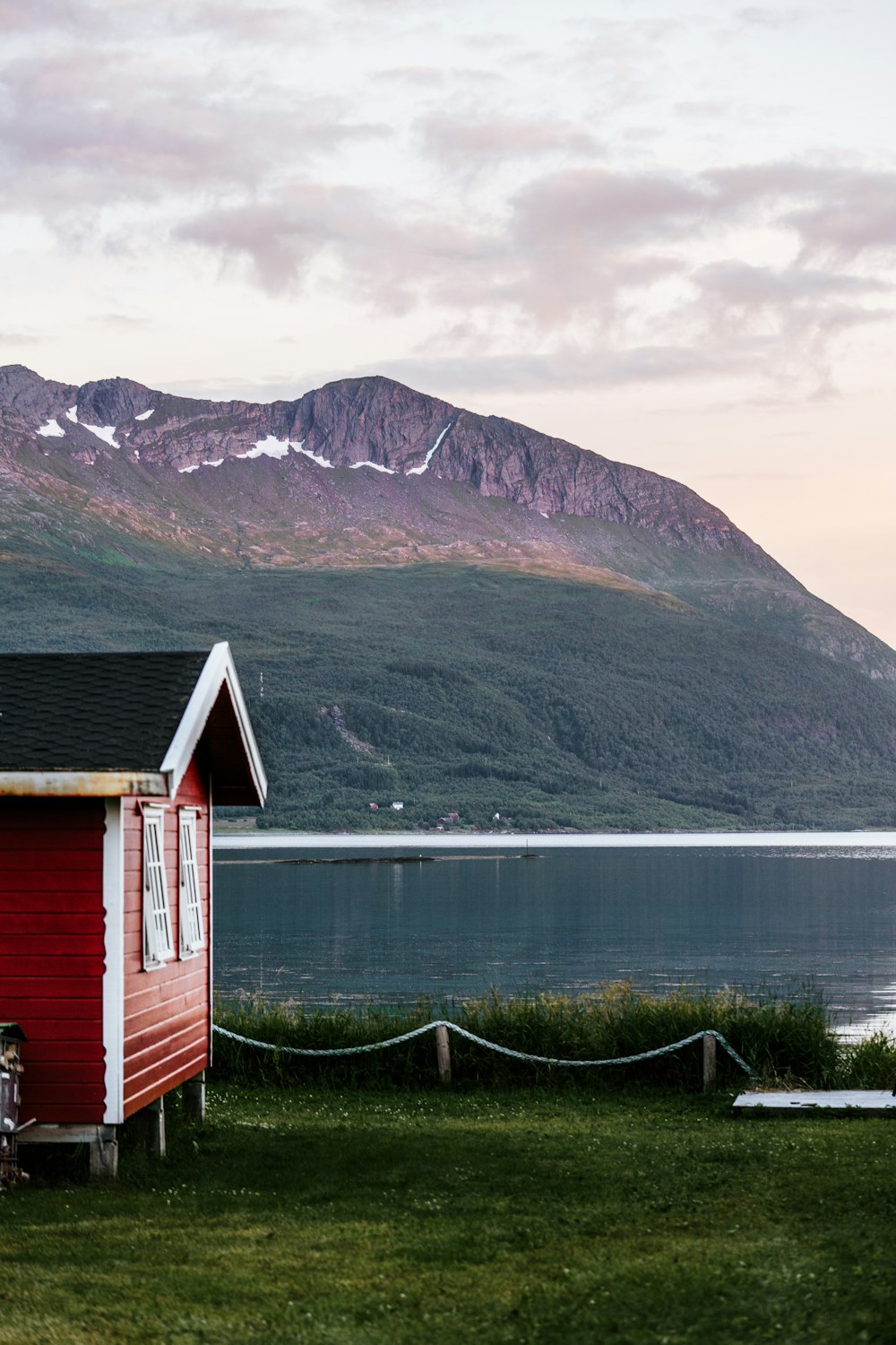 a small red house sitting on top of a lush green field