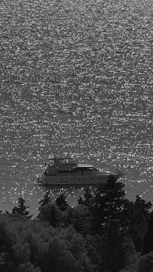 Sunlight glistening off gentle ocean waves beside a sleek yacht.