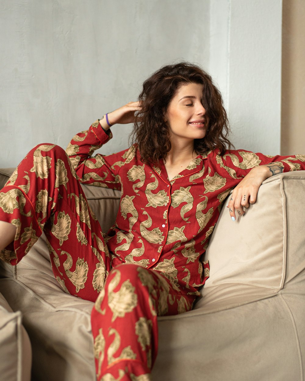 a woman sitting on a couch wearing a red and gold pajamas
