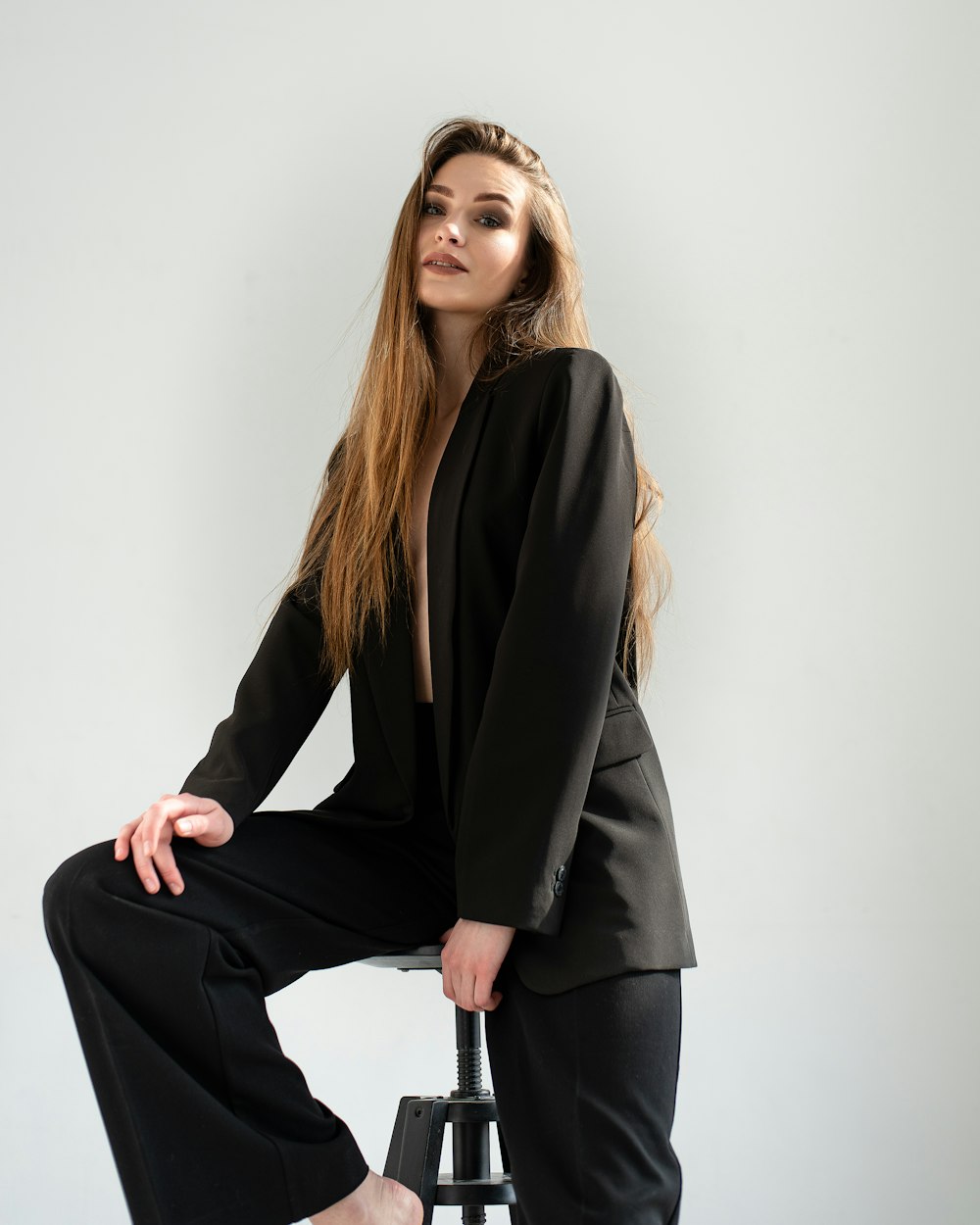 a woman sitting on a stool with her legs crossed