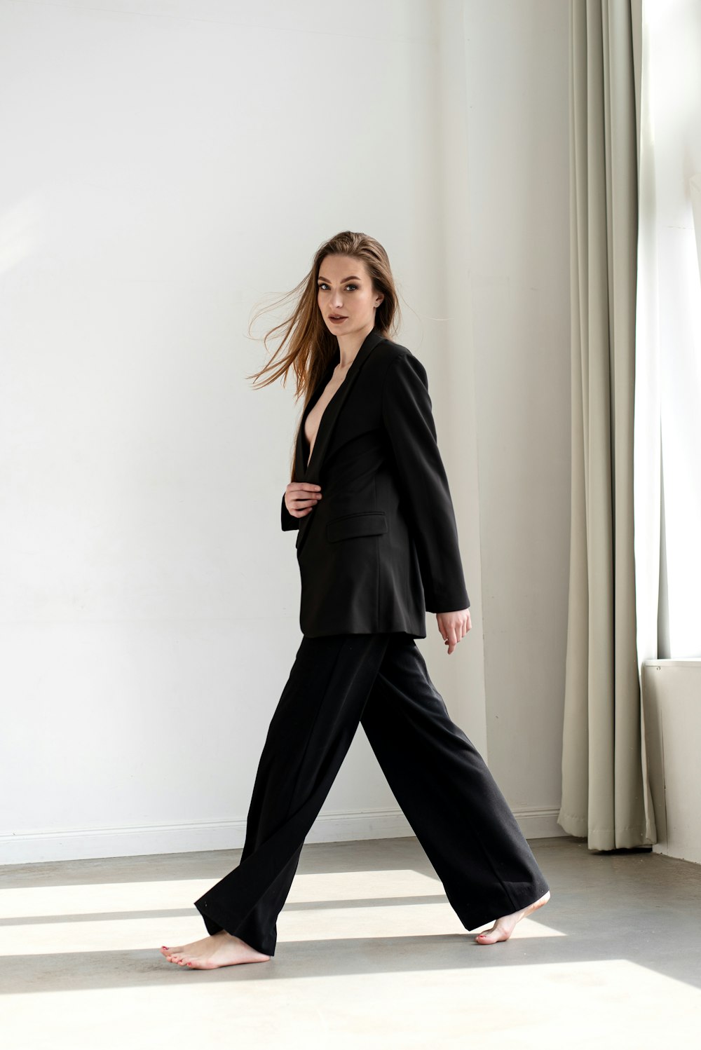 a woman in a black suit is walking