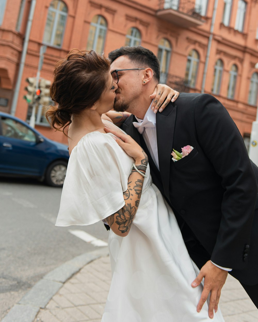 a bride and groom kissing in front of a building