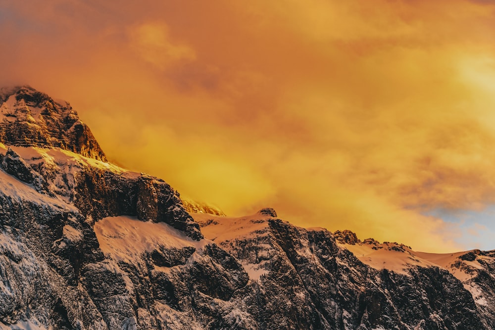 a mountain covered in snow under a cloudy sky