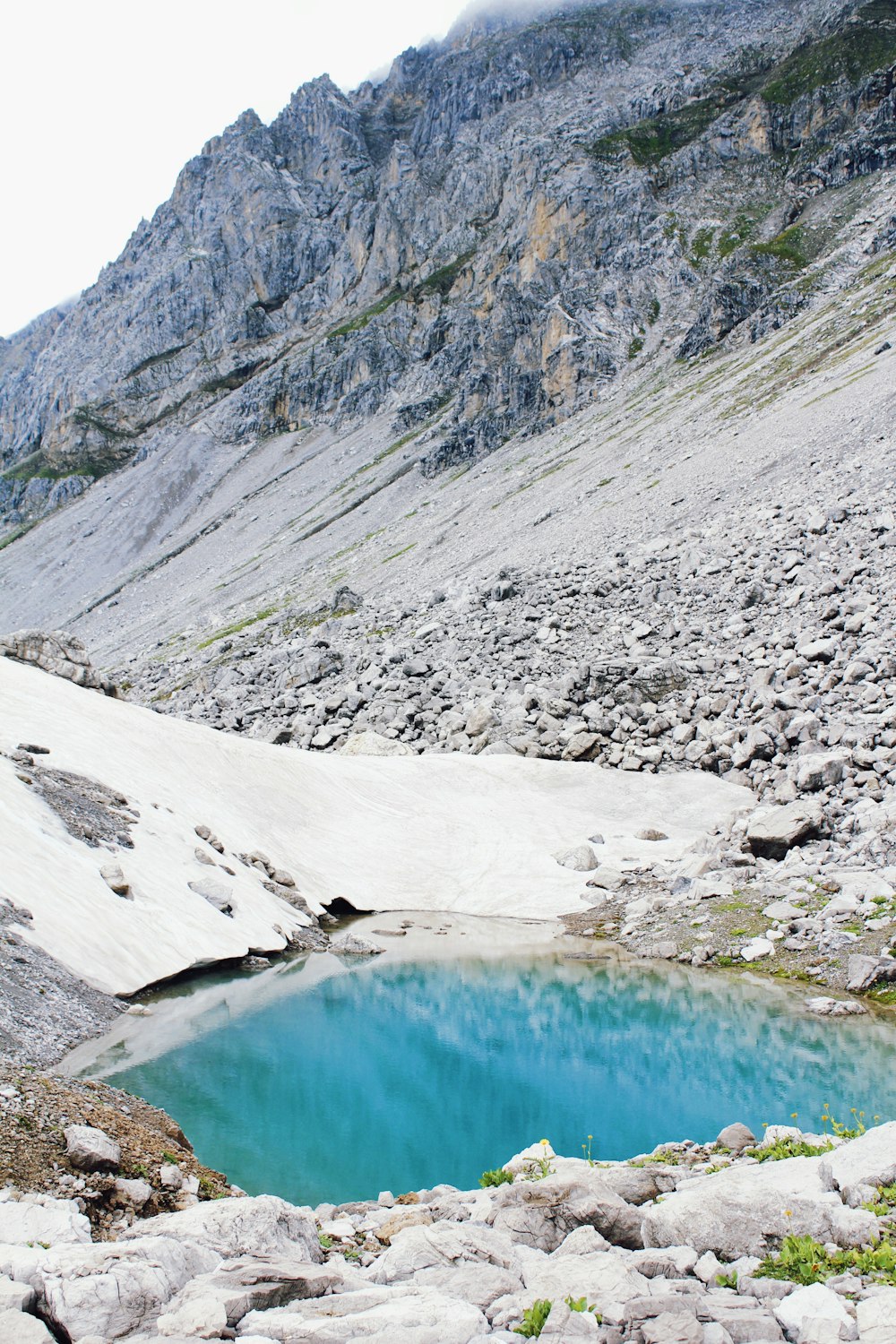 a blue pool of water in the middle of a mountain