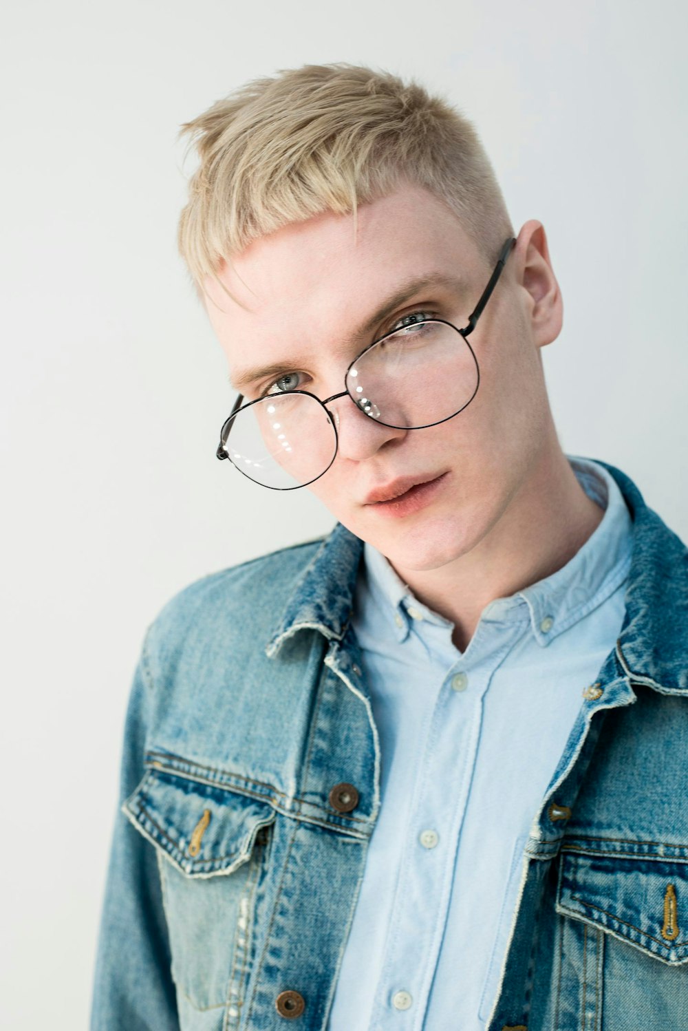 a man wearing glasses and a denim jacket