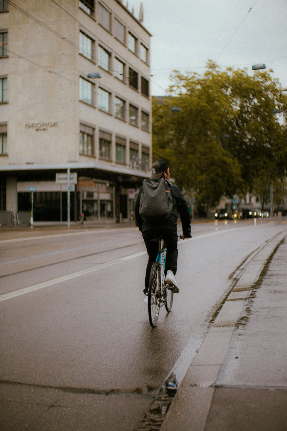 a man riding a bike down a street next to a tall building