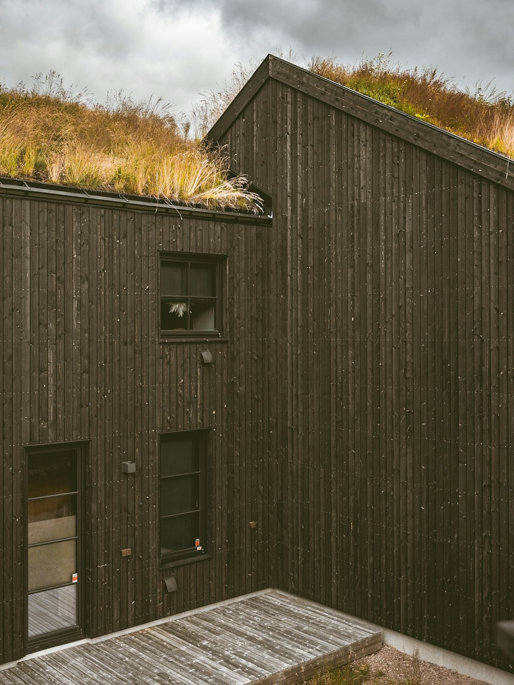 a building with a green roof and a wooden deck