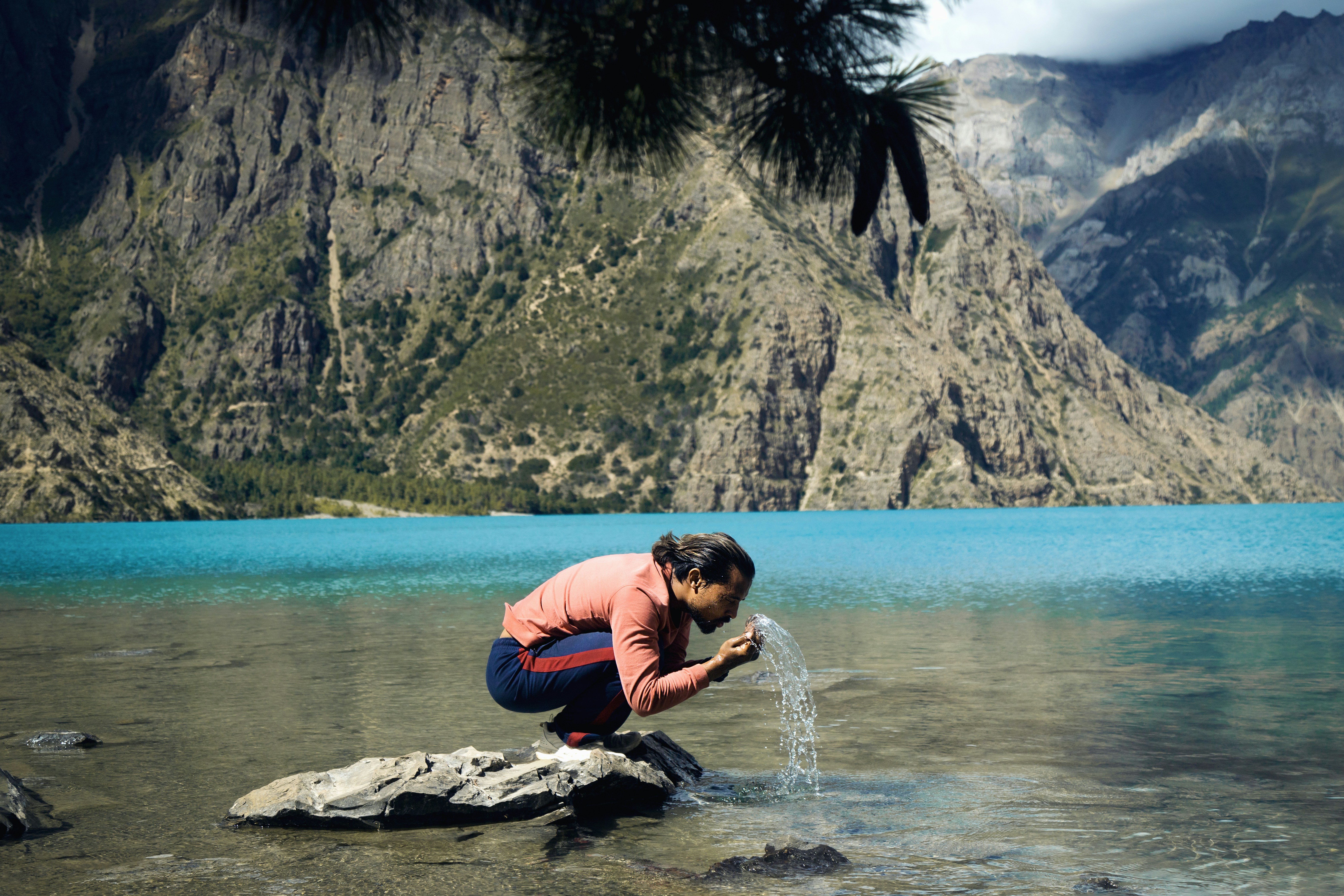 a person kneeling on a rock near a body of water 풍경 사진