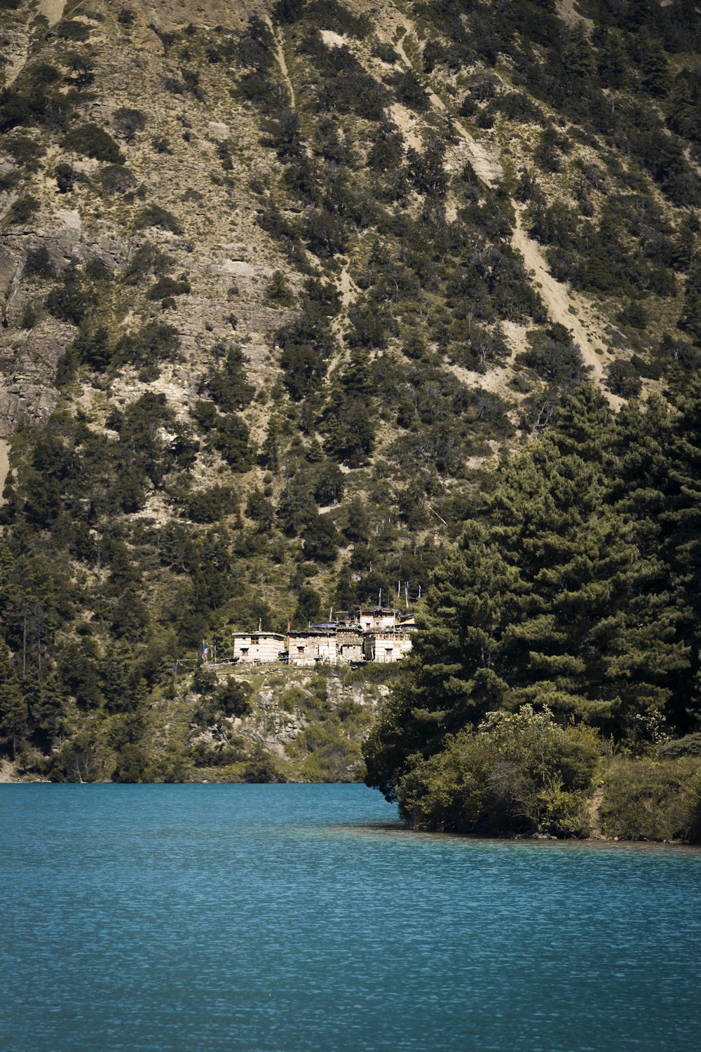 a house on the side of a mountain next to a body of water