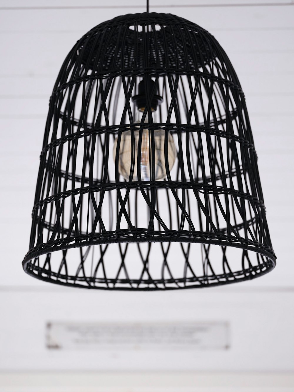 a black bird cage hanging from a ceiling
