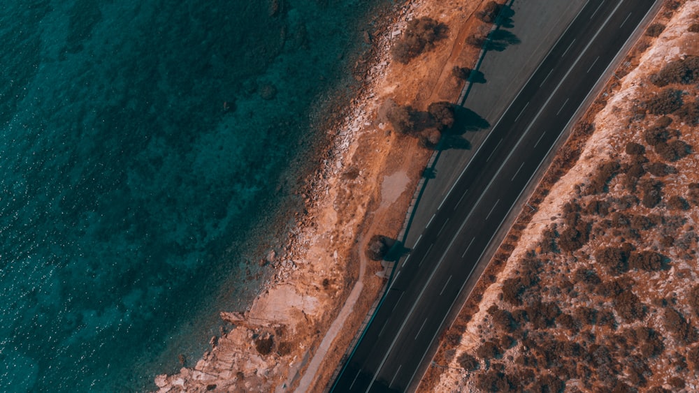 an aerial view of a road next to a body of water