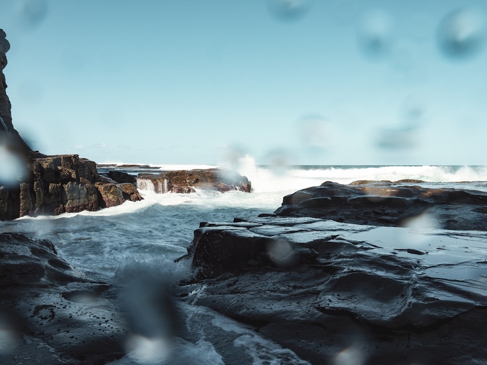 a view of the ocean through a rainy window