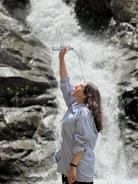 A happy person filling their water bottle at a modern water refill station outdoors.