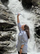 An influencer demonstrating a portable water filtration system beside a flowing mountain stream