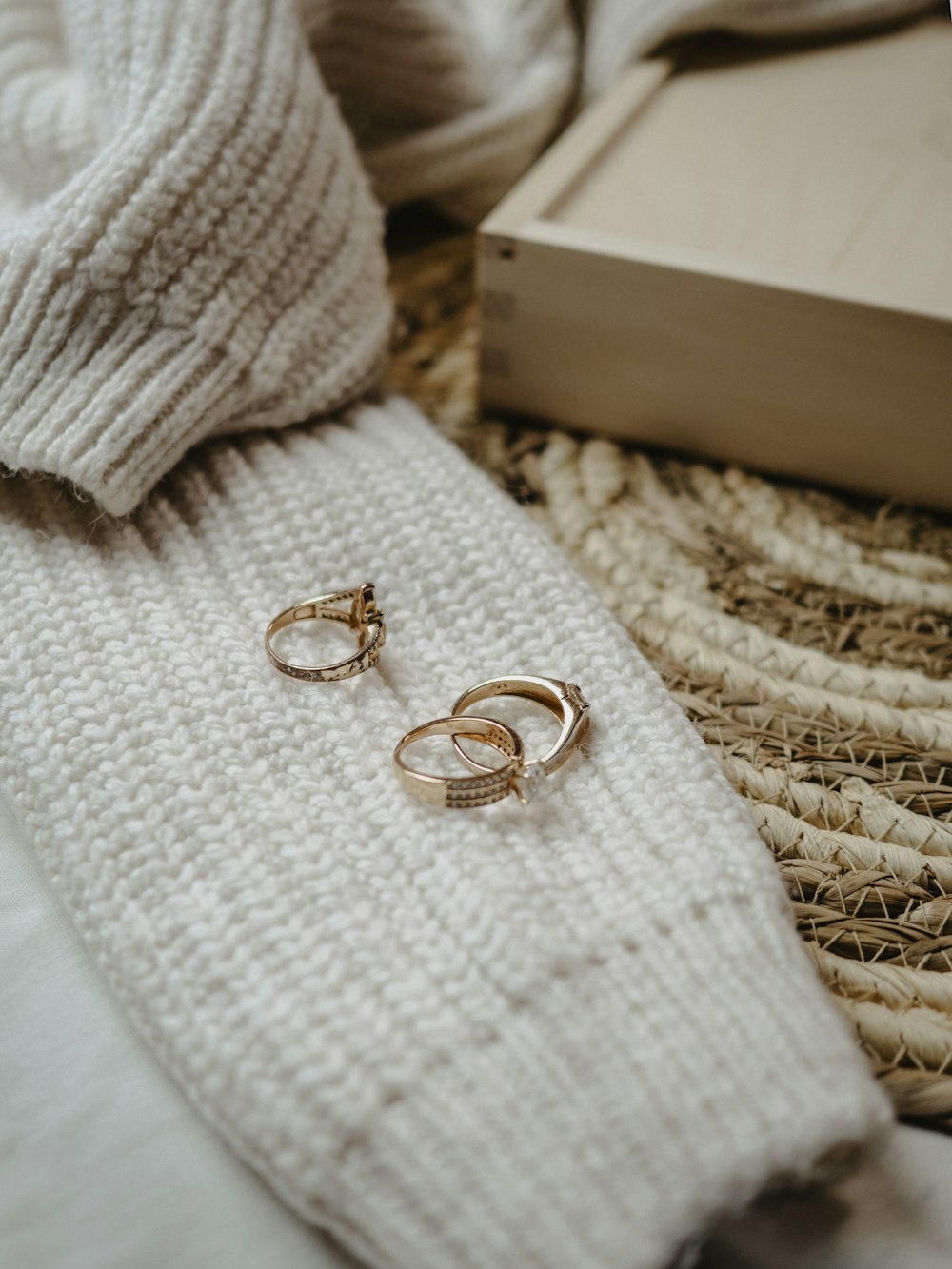 a pair of gold rings sitting on top of a white blanket
