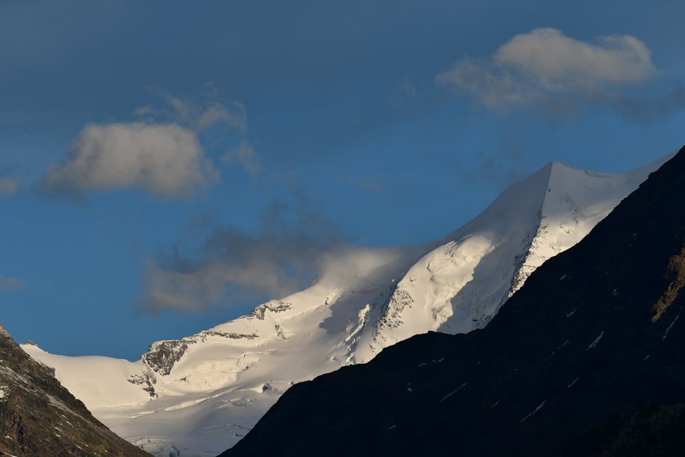 a snow covered mountain with clouds in the sky