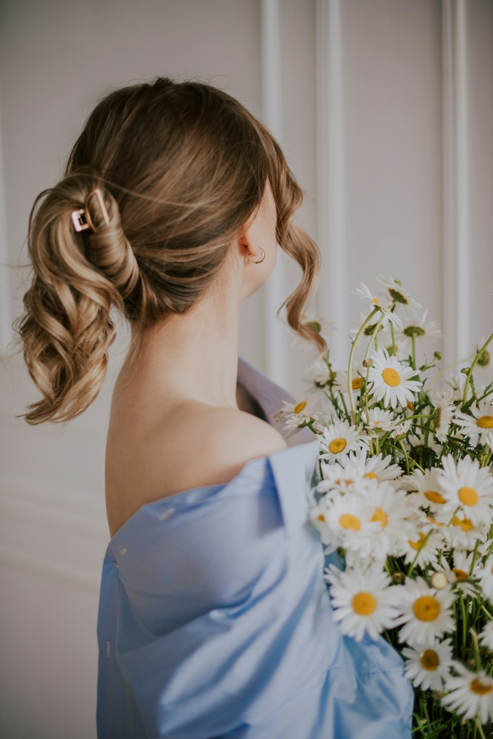 a woman in a blue dress holding a bouquet of daisies