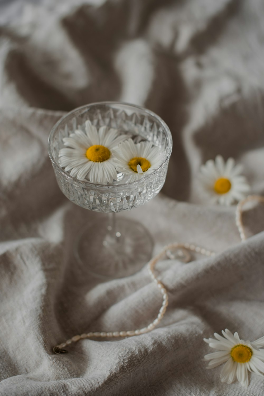a small glass bowl with daisies in it
