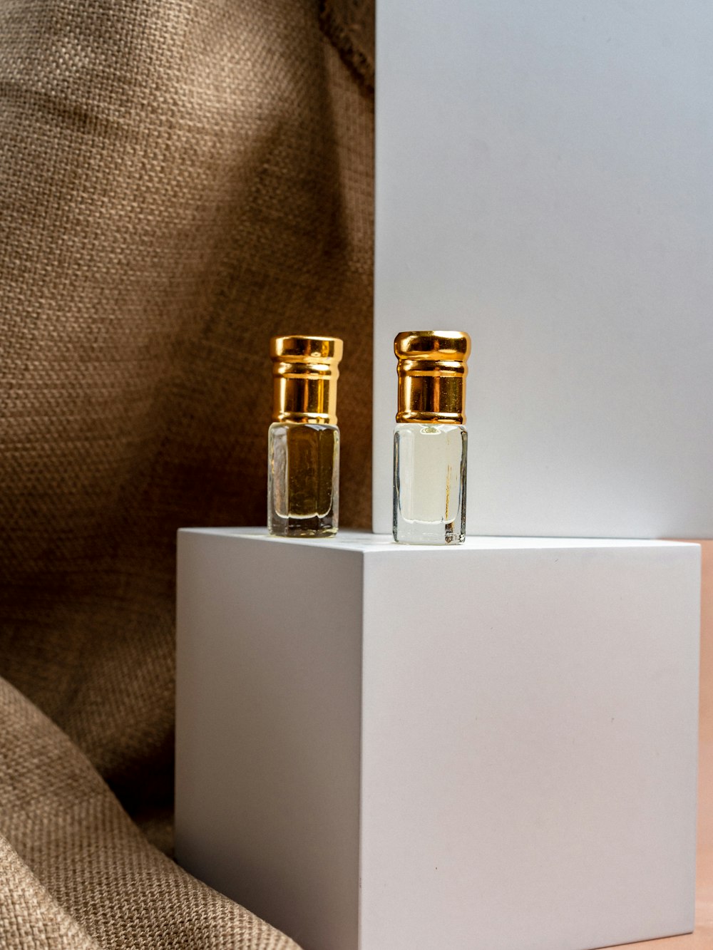two bottles of perfume sitting on top of a white box