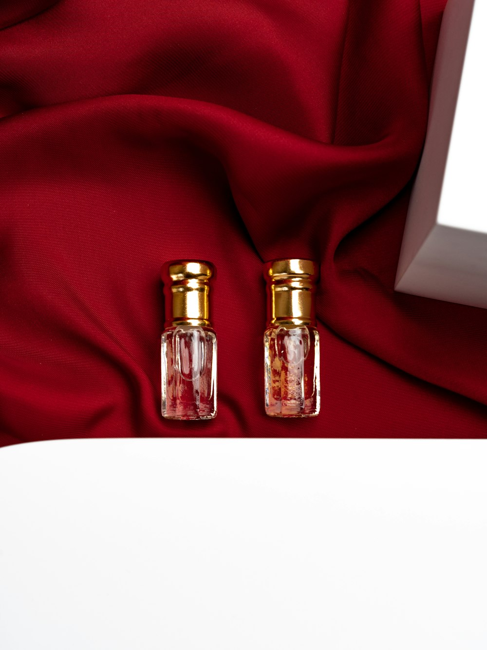two bottles of perfume sitting on a red cloth