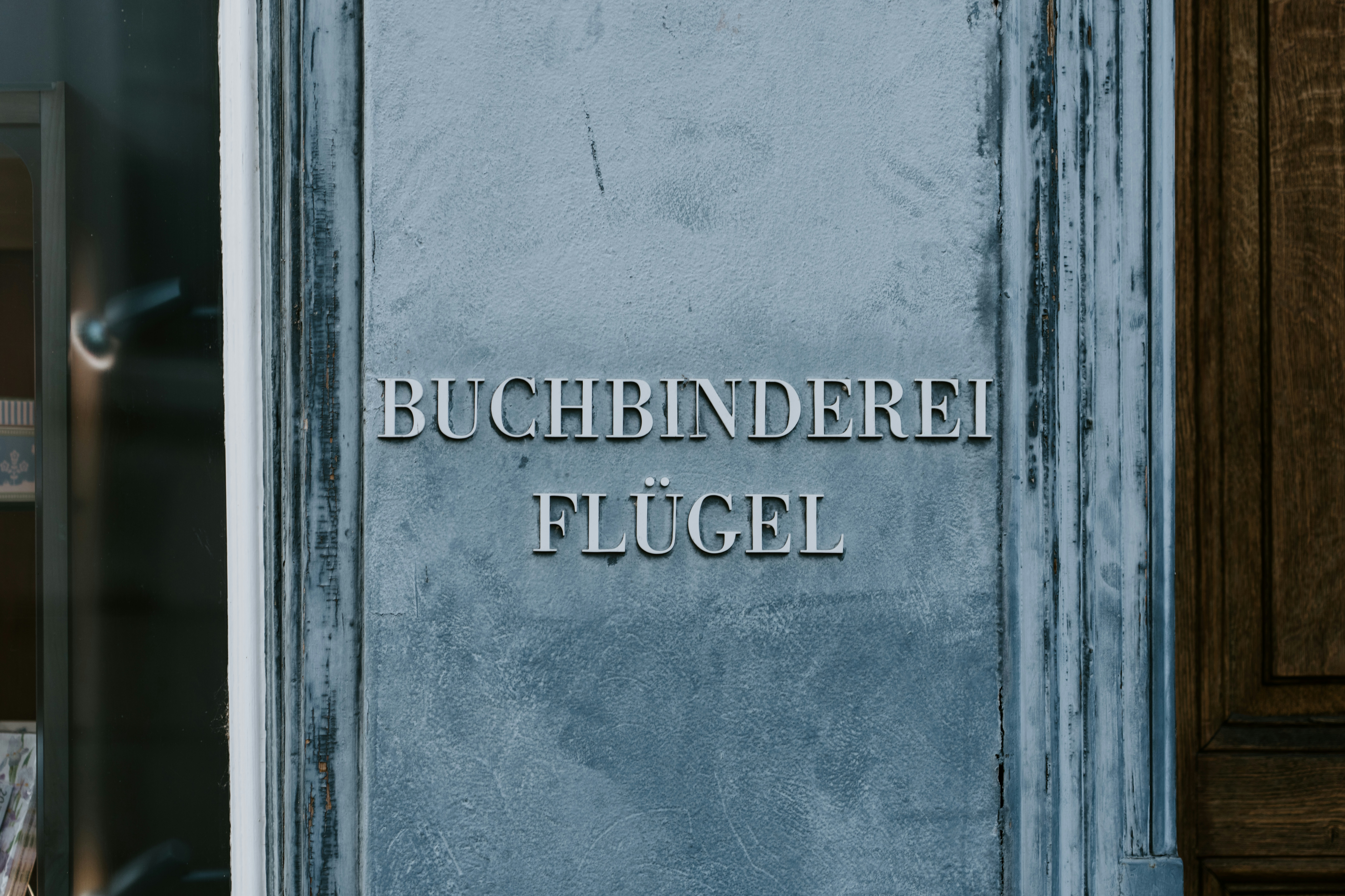 a blue door with a sign that reads buchbinderei flugel