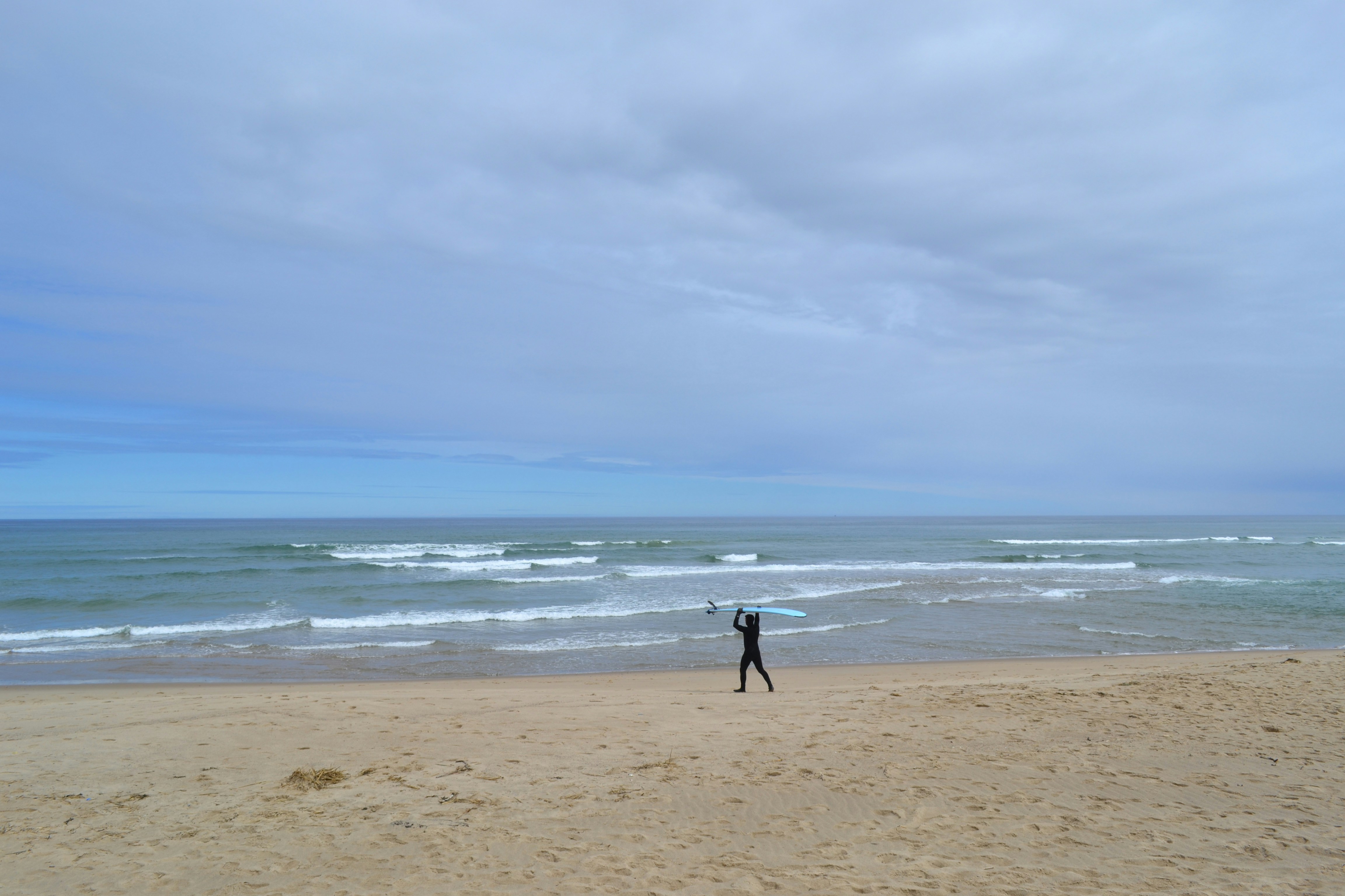 a person standing on a beach holding a surfboard
