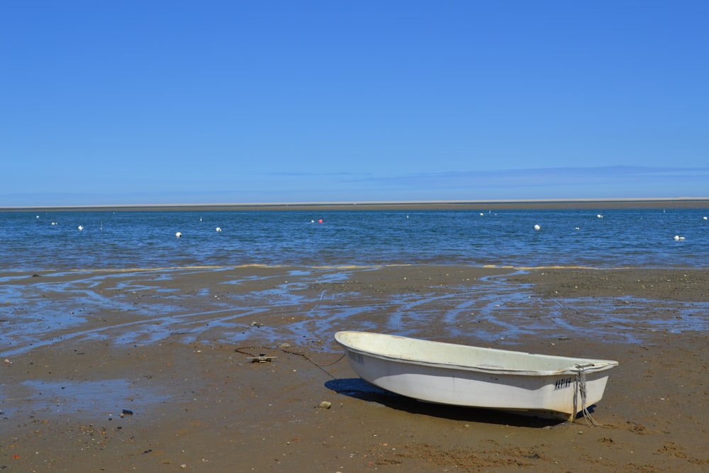 a white boat sitting on top of a sandy beach