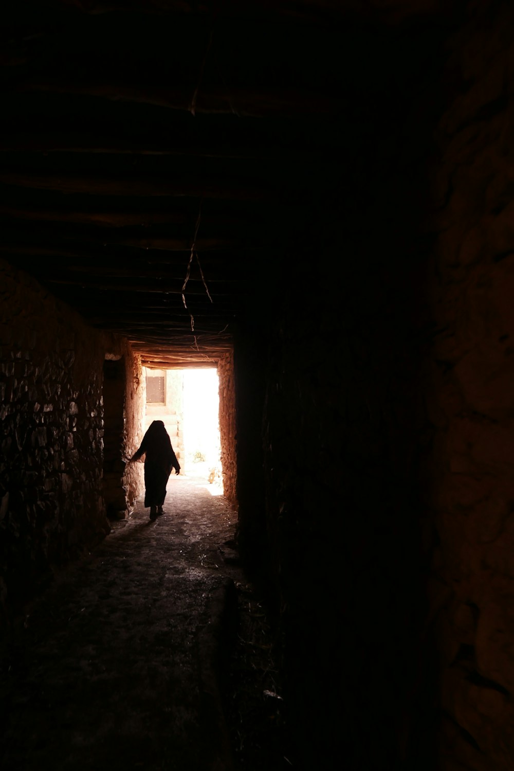 a dark tunnel with a person walking out of it
