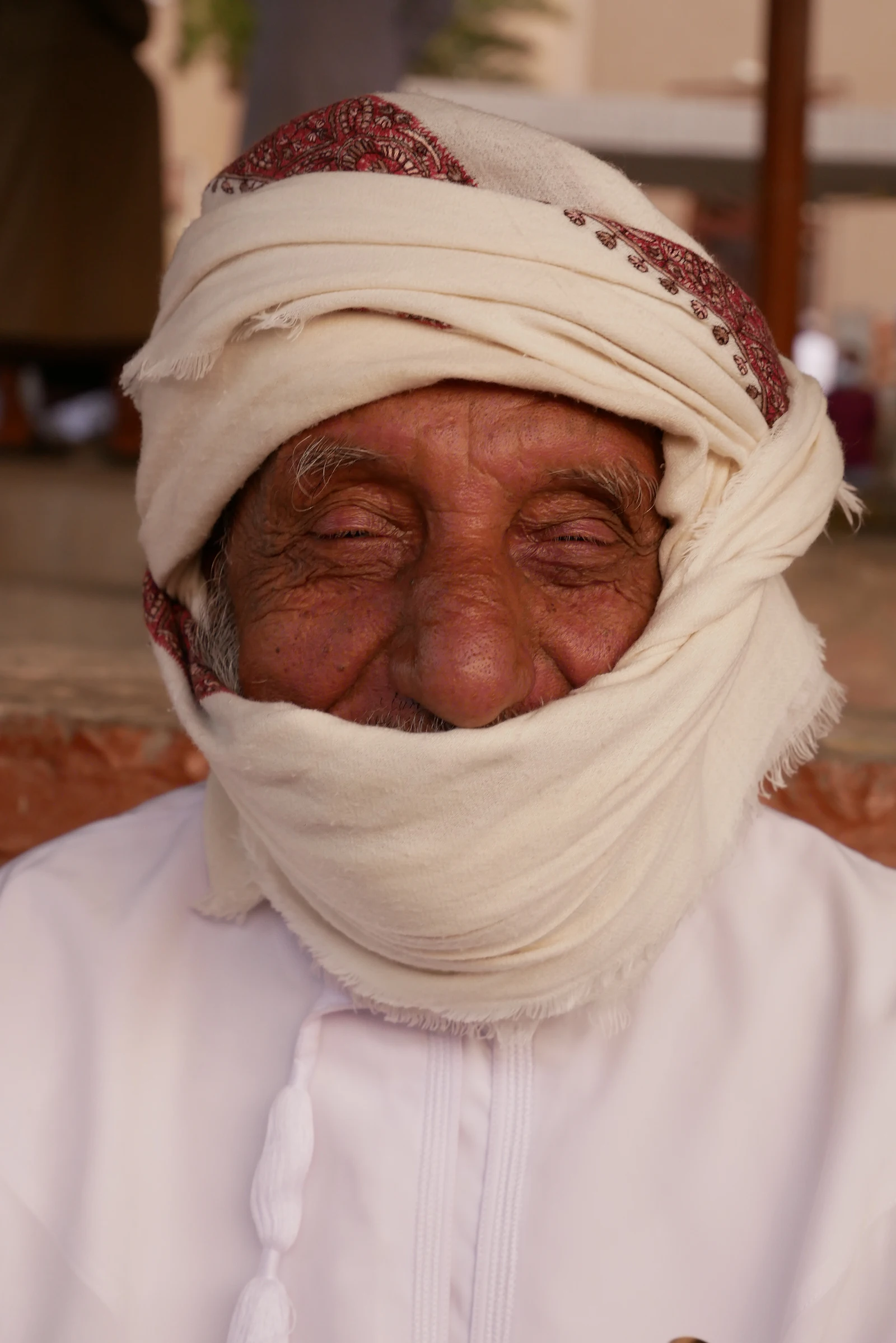 Portrait of an older man with a white beard and turban, smiling.