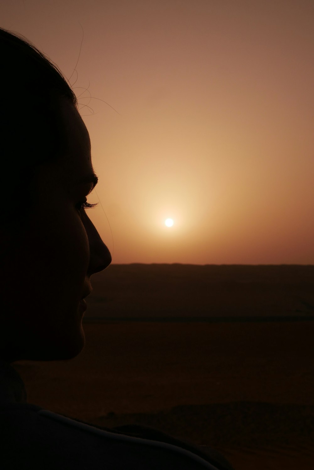 a woman standing in front of a sunset