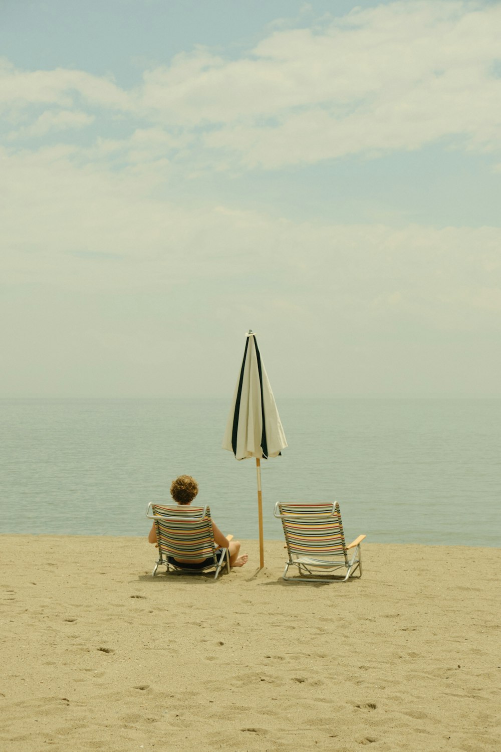 우산 아래 해변에 앉아있는 사람