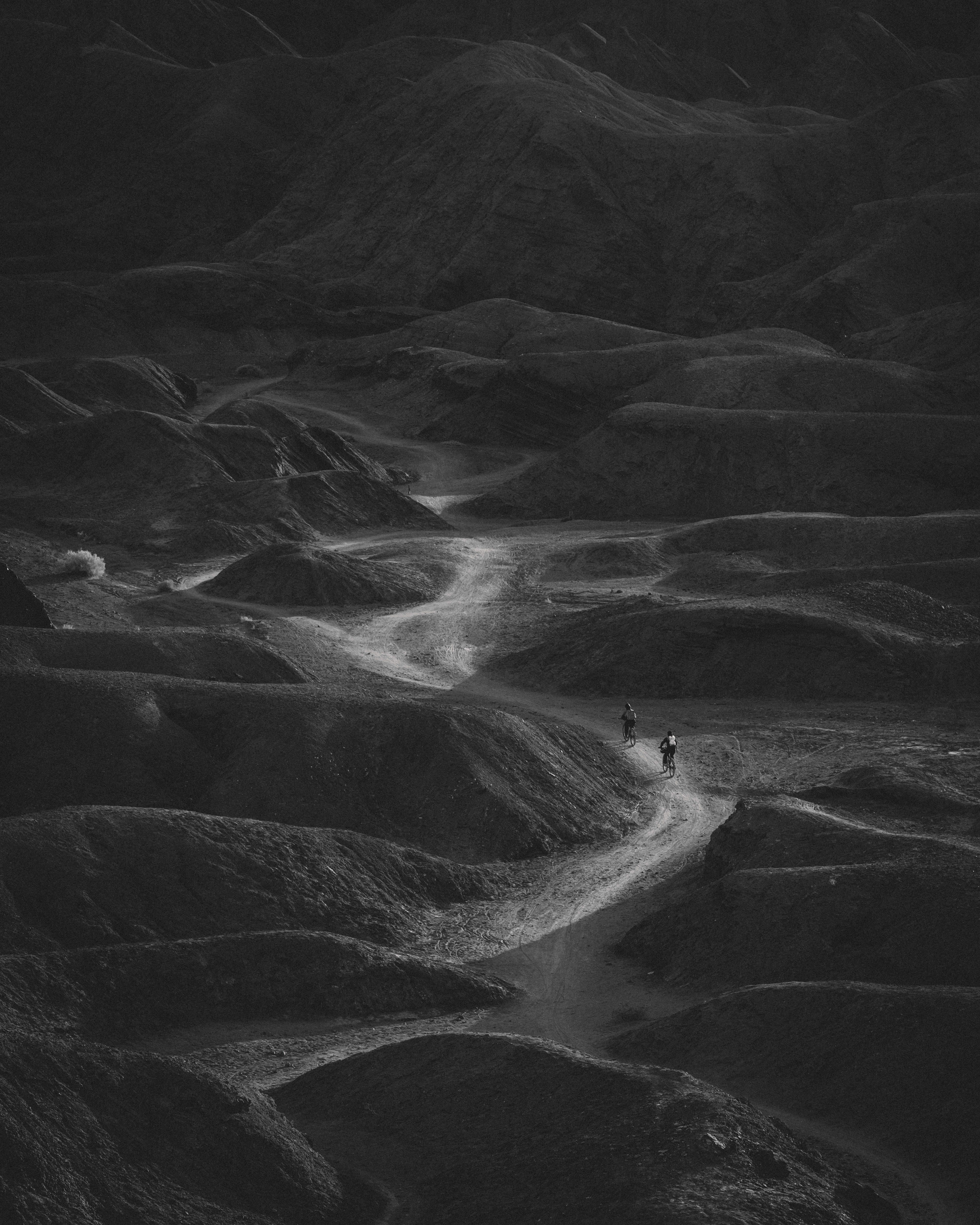 a black and white photo of a person riding a bike