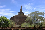 The majestic Great Stupa at Sanchi surrounded by lush greenery under a bright blue sky.