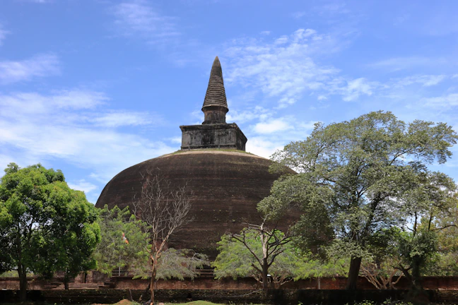 The majestic Great Stupa at Sanchi surrounded by lush greenery under a bright blue sky.