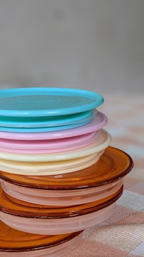 Stacked transparent plastic containers with colorful lids, displayed on a store shelf.