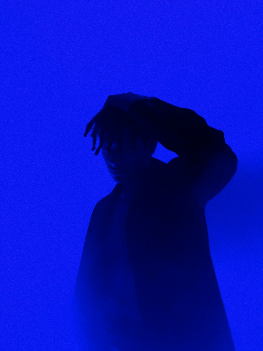 a man with dreadlocks standing in front of a purple background
