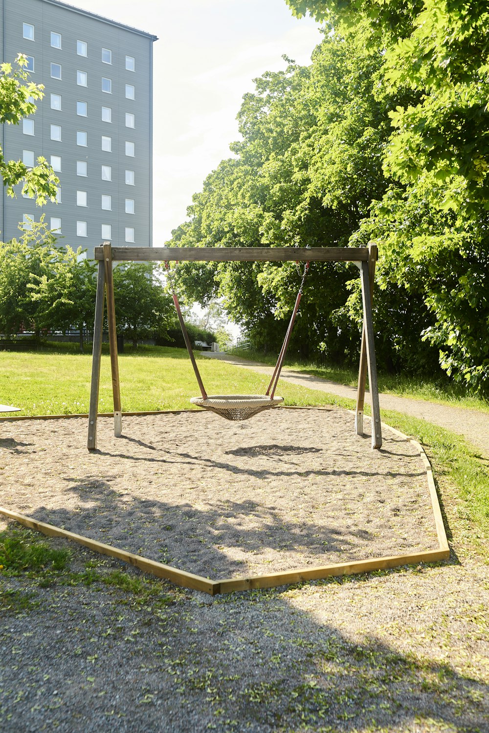 a swing set in a park with a building in the background