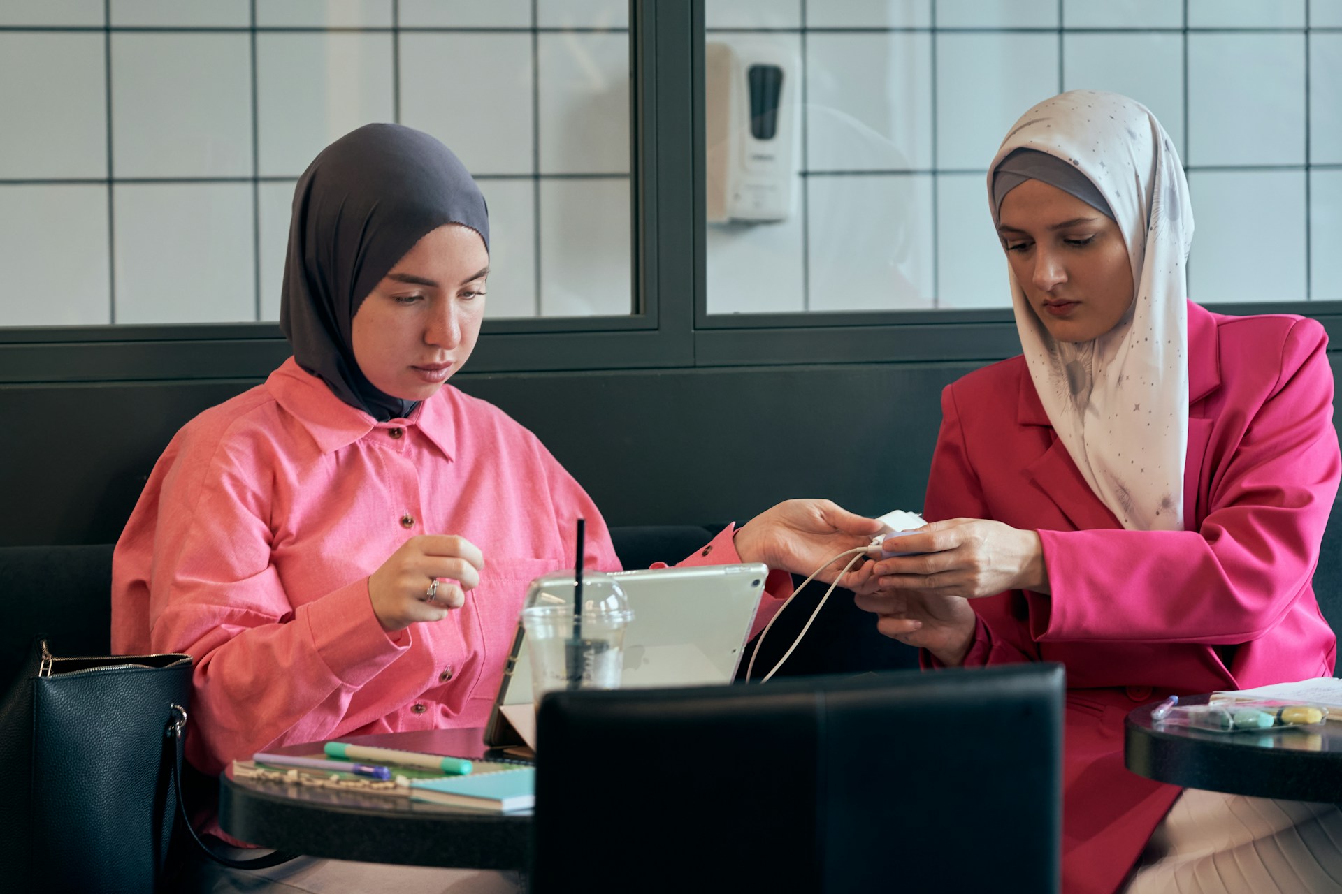 two women sitting at a table looking at a cell phone
