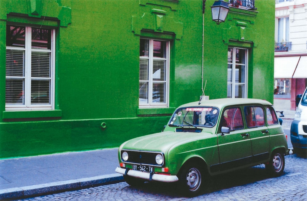 a green car parked on the side of a street